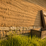 mur en pisé avec soubassement en pierre et herbe